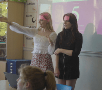 2 peer educators stand at the front of the classroom